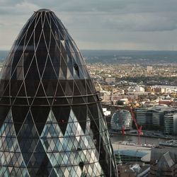 Gherkin building in city against cloudy sky