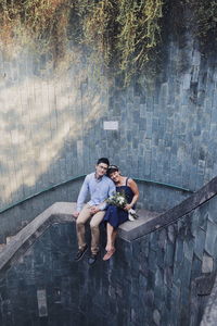 Full length of young man sitting on wall