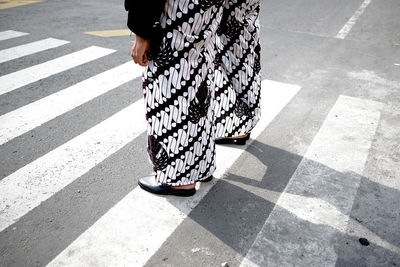 Low section of woman walking on road