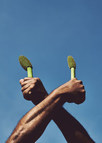 Low angle view of person hand against blue sky