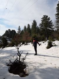 Woman standing on snow covered land against sky