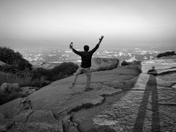 Rear view of man with arms outstretched standing on land