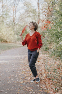 Beautiful middle age caucasian woman with short curly hair in park outdoor. 