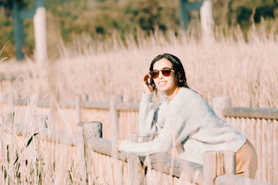 Portrait of young woman wearing sunglasses standing on field