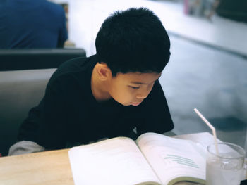 Boy reading book on table at home