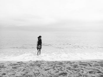 Rear view of man walking on beach against sky