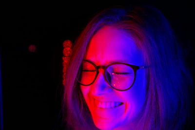 Portrait of young woman wearing eyeglasses against black background