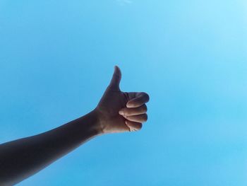 Low angle view of hand against blue sky