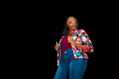 Full length of woman standing against black background