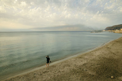 Rear view of man looking at sea against sky