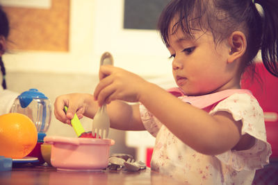 Cute girl holding ice cream on table at home