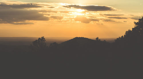 Scenic view of silhouette mountains against orange sky