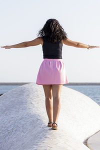 Rear view of woman standing by sea against sky