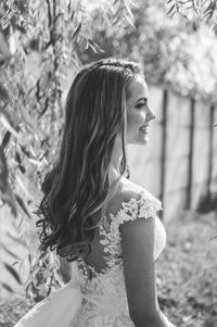 Side view of young woman looking away against trees