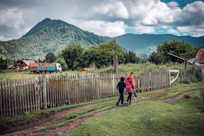 Rear view of men walking on landscape against sky