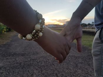 Close-up of people hands against sky during sunset