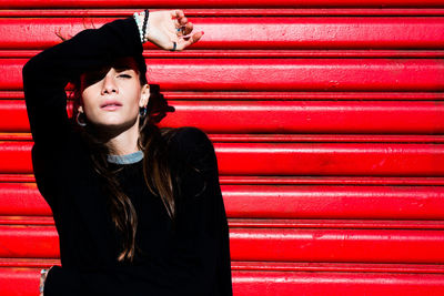 Portrait of beautiful young woman standing against corrugated iron