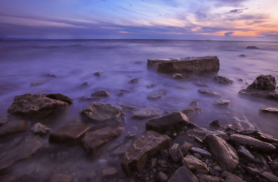 A rocky seascape at sunrise with waves flowing over harsh granite rocks.s violet sea. mystic scene.