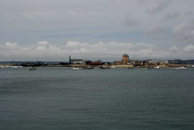 Sea by cityscape against sky