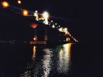 Illuminated bridge over water at night