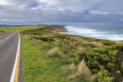 Scenic view of road by sea against sky