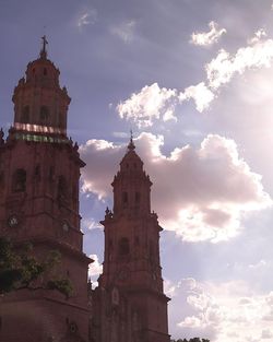 Low angle view of bell tower against cloudy sky