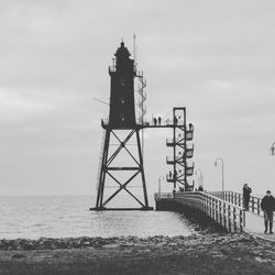 Lighthouse at beach against sky