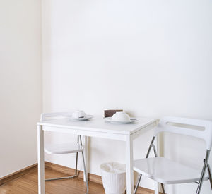 Empty chairs and table against wall at home