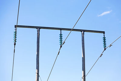 Low angle view of electricity pylon against clear blue sky