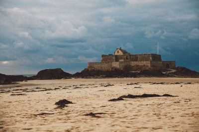 View of birds on sand against cloudy sky