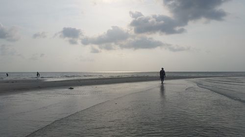 Scenic view of beach against cloudy sky