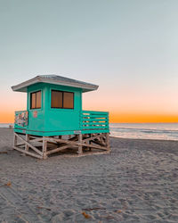 Lifeguard hut on beach against sky during sunset