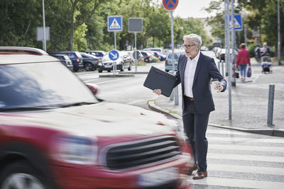 Shocked senior male professional crossing by speeding car