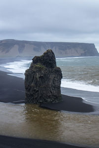 Rock formation on beach against sky