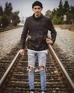 Portrait of young man standing on railroad track