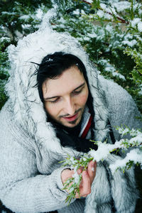 Man wearing warm clothing by snow covered plants