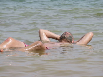 Shirtless man with mud on face while relaxing in sea