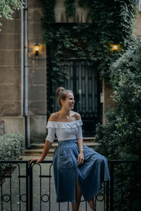 Young woman looking away while standing against plants