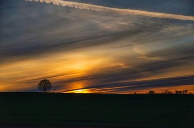 Scenic view of silhouette field against sky at sunset