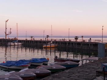 Boats moored in calm sea at sunset