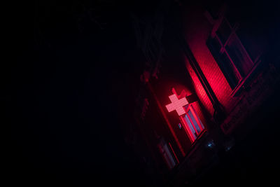 Low angle view of illuminated red neon cross at night