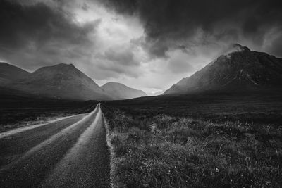 Road leading towards mountains against sky