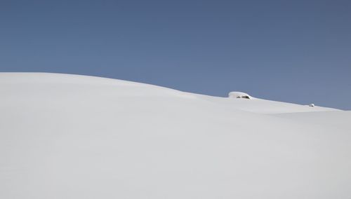 View of snow covered landscape against clear blue sky