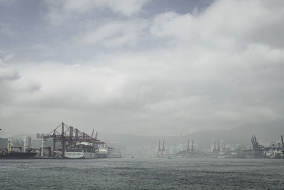 Commercial dock in sea against cloudy sky