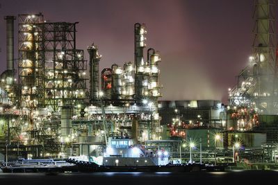 Illuminated factory against sky at night