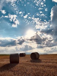 Hay bales on field against sky