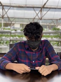 Portrait of man using mobile phone while sitting on table