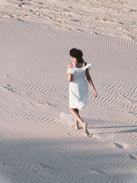 Full length of woman walking on sand at beach