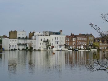 Buildings by lake against clear sky