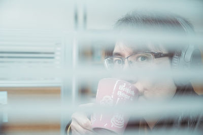 Portrait of man holding glass window